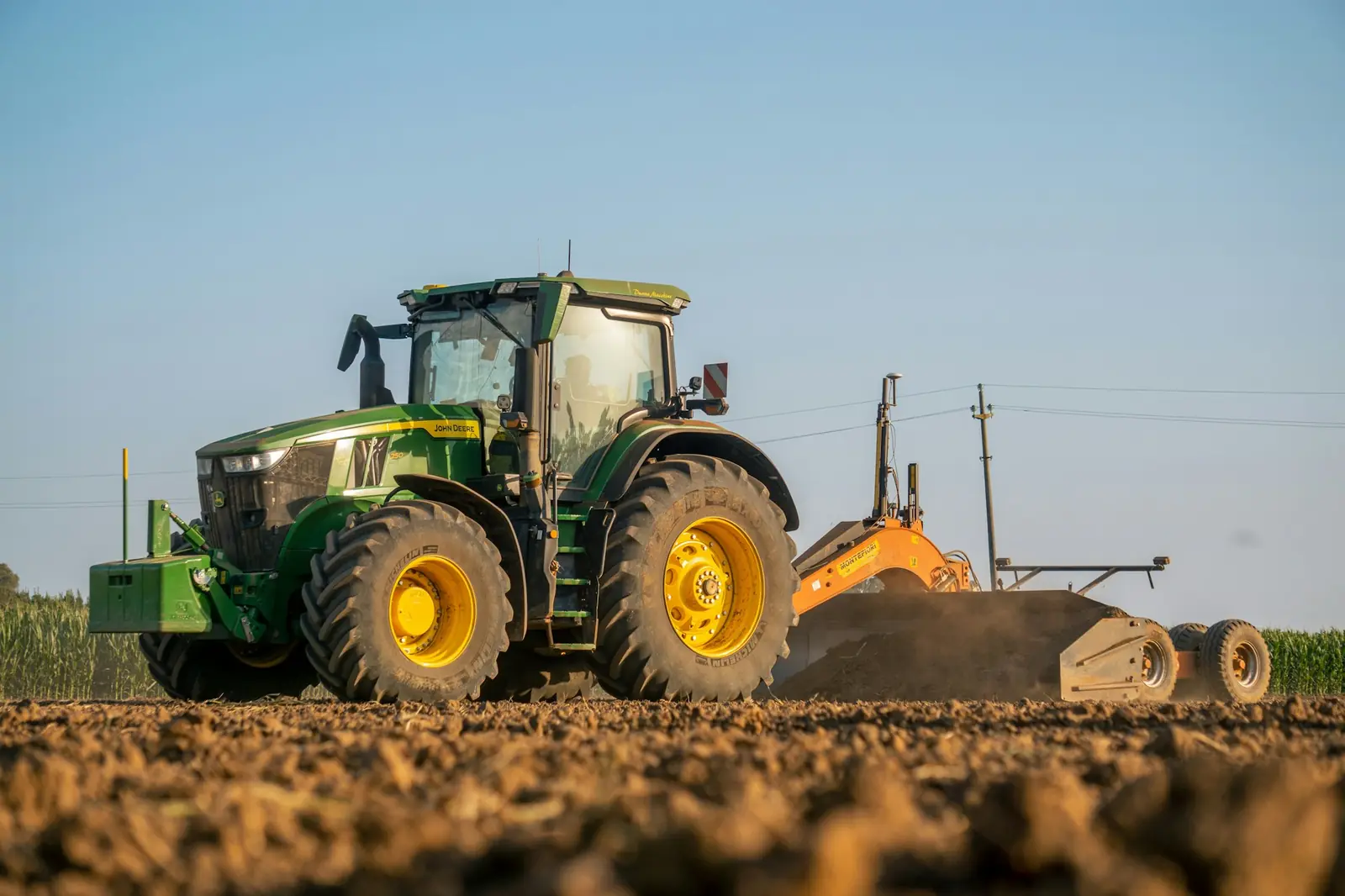 Tractor with a land-levelling implement on bare soil